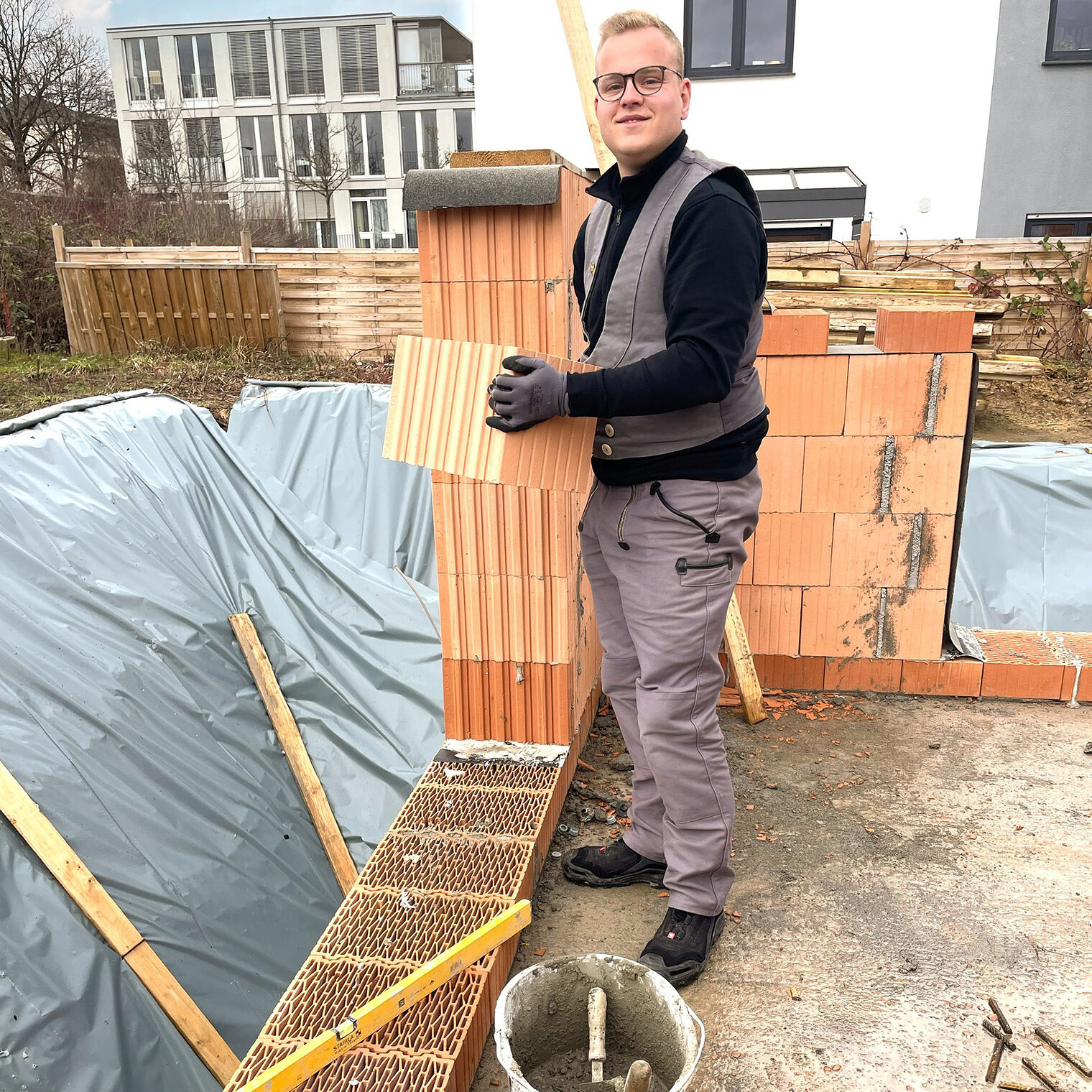 Florian Kühn auf einer Baustelle mit einem Baustein in der Hand