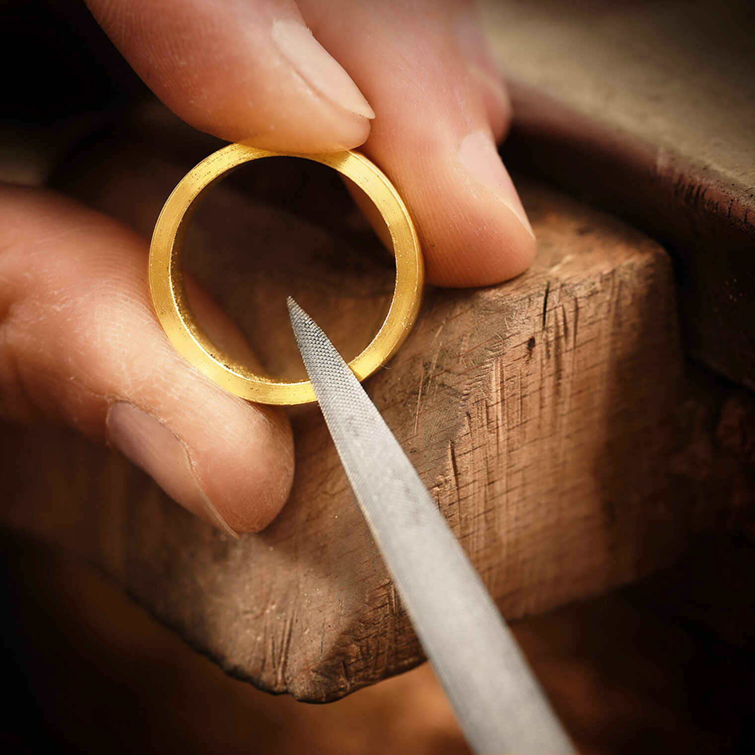 Finger halten einen Goldring, an dem gerade gefeilt wird. 