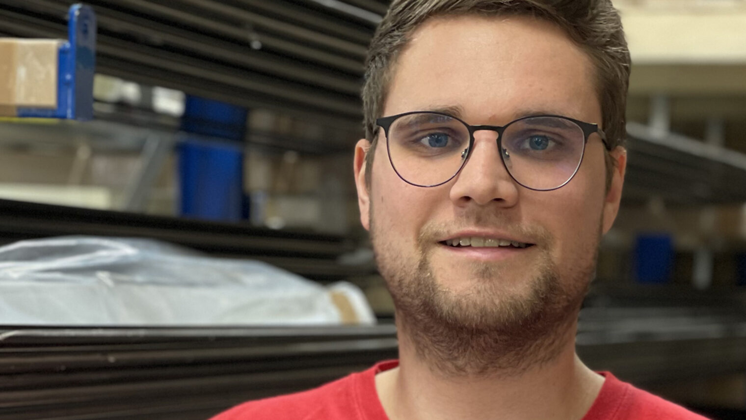 Christoph Pfündner, Meister im Rollladen- und Sonnenschutztechnikerhandwerk in seinem Lager mit einem Rollladen unter dem Arm.