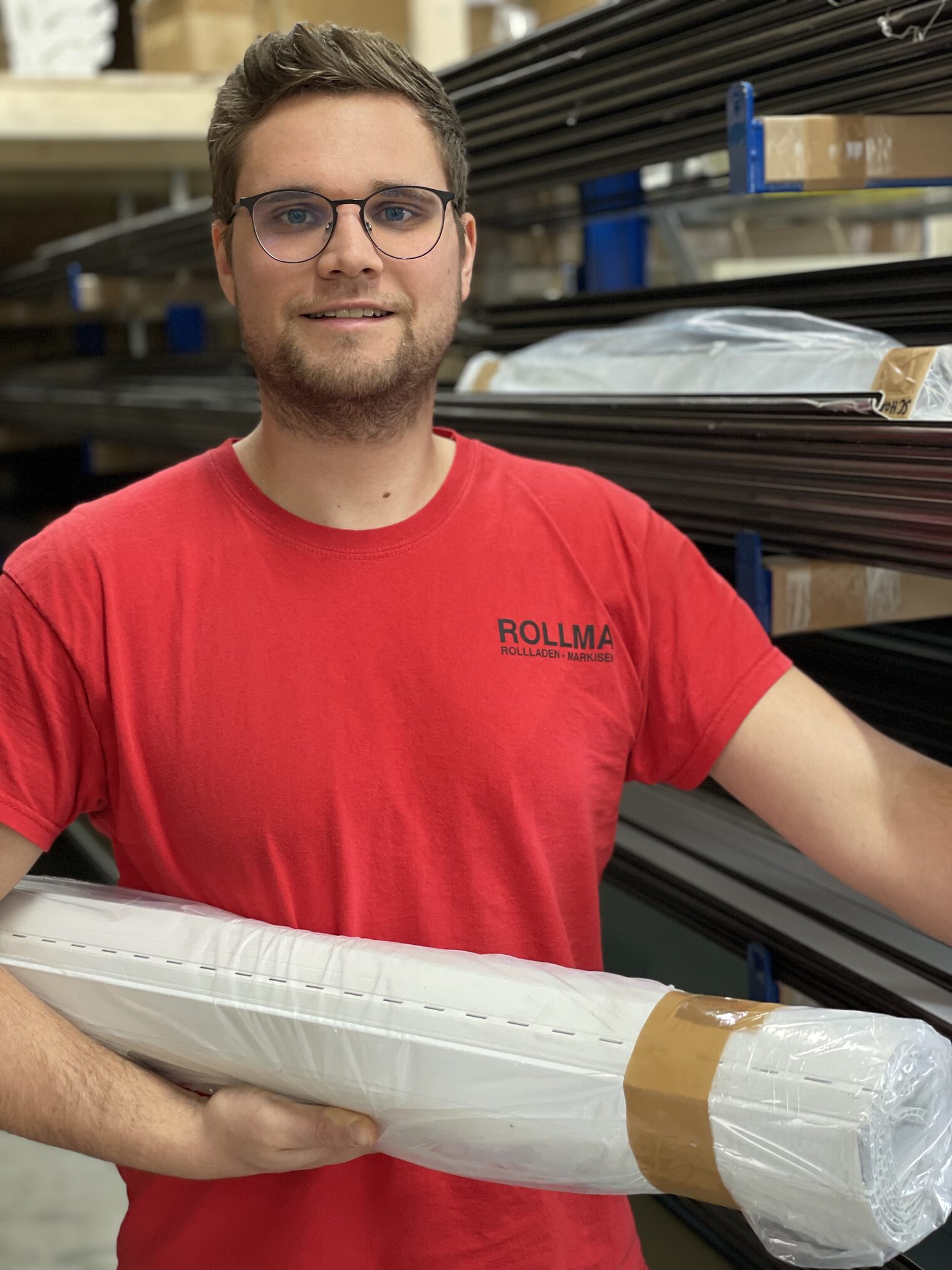 Christoph Pfündner, Meister im Rollladen- und Sonnenschutztechnikerhandwerk, in seinem Lager mit einem Rollladen im Arm. 