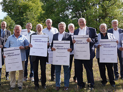 Gruppe der Handwerkerinnen und Handwerker die einen Goldenen Meisterbrief erhalten haben, auf der Wiese der Handwerkskammer