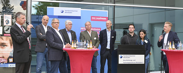 Das Bild zeigt die von Kai Völker, vom Hessischen Rundfunk, moderierten Talkrunde mit Landrat Frank Kilian, Oberbürgermeister Gert-Uwe Mende, dem Geschäftsführer der Agentur für Arbeit Wiesbaden, Stephen Spieker, Kammerpräsident Stefan Füll, Hauptgeschäftsführer Bernhard Mundschenk und Kreishandwerksmeister Holger Balz vor dem Eingang des Berufsbildungs- und Technologiezentrum.