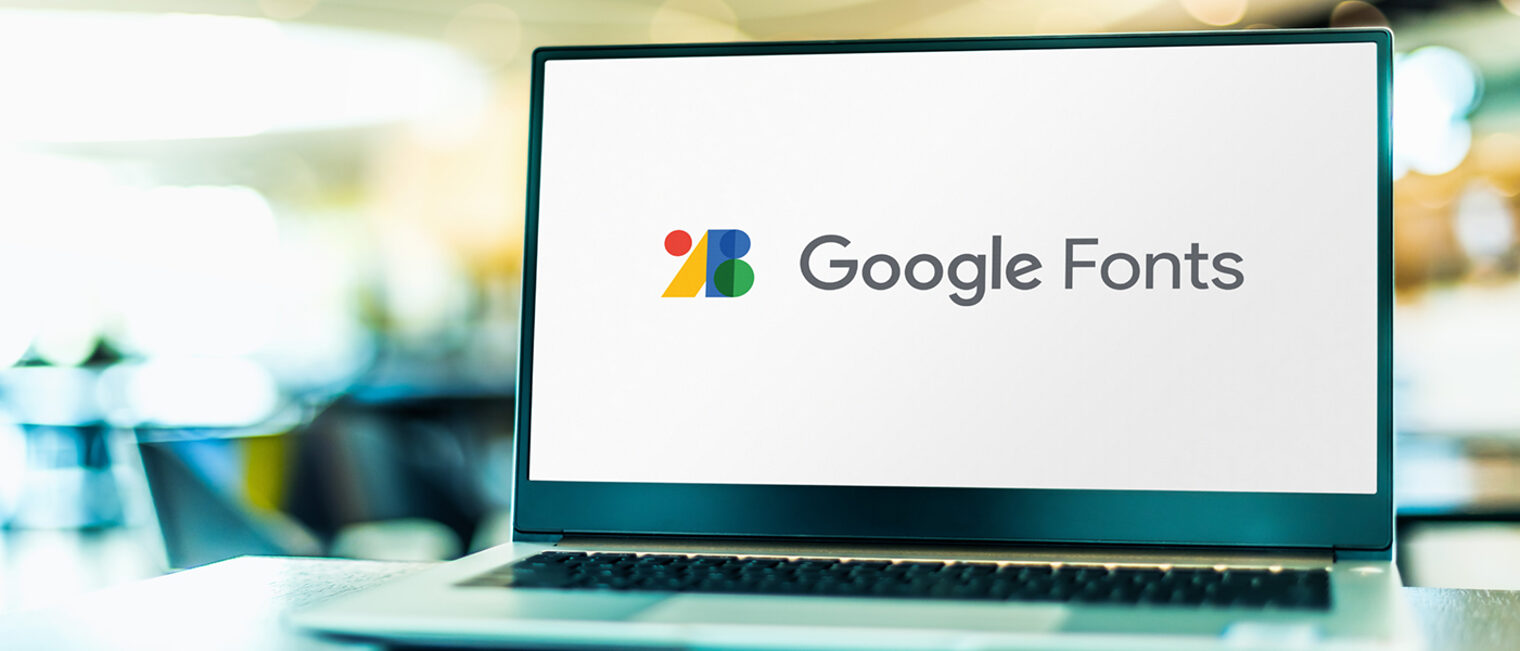 Google Fonts Logo auf dem Bildschirm eines Laptops, der auf dem Tisch steht. Der Hintergrund ist nur verschwommen wahrnehmbar.
