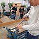 Ein Schüler besucht die Berufsorientierungswoche und ist in der Metall-Lehrwerkstatt. Die Aufgabe besteht darin, einen Würfel herzustellen. Auf dem Bild ist er an der Werkbank und schleift den eingespannten Würfel. 