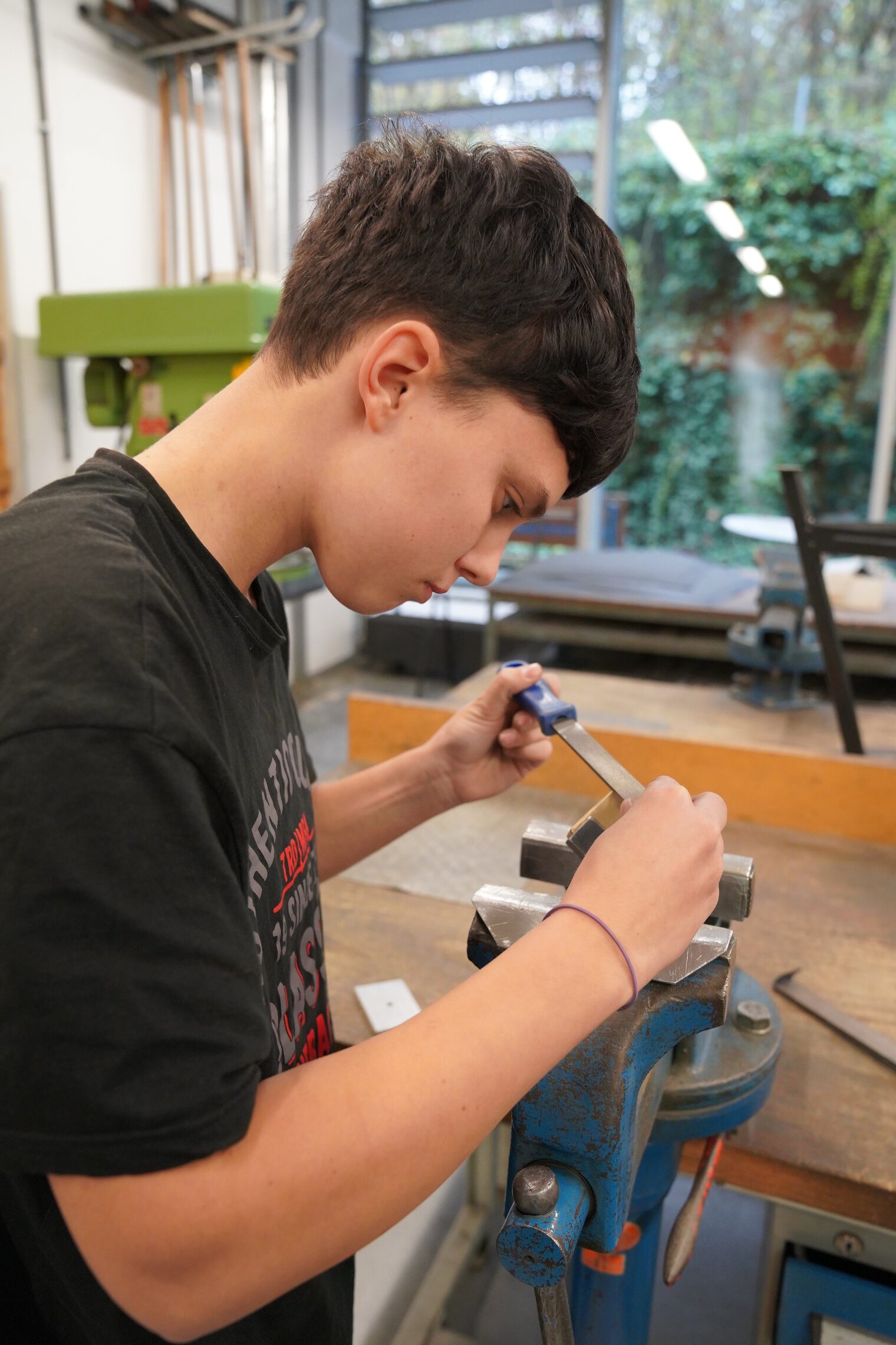 Ein Schüler besucht die Berufsorientierungswoche und ist in der Metall-Lehrwerkstatt. Die Aufgabe besteht darin, einen Würfel herzustellen und zeigt diesen beim Schleifen an der Werkbank. 