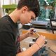 Ein Schüler besucht die Berufsorientierungswoche und ist in der Metall-Lehrwerkstatt. Die Aufgabe besteht darin, einen Würfel herzustellen und zeigt diesen beim Schleifen an der Werkbank. 