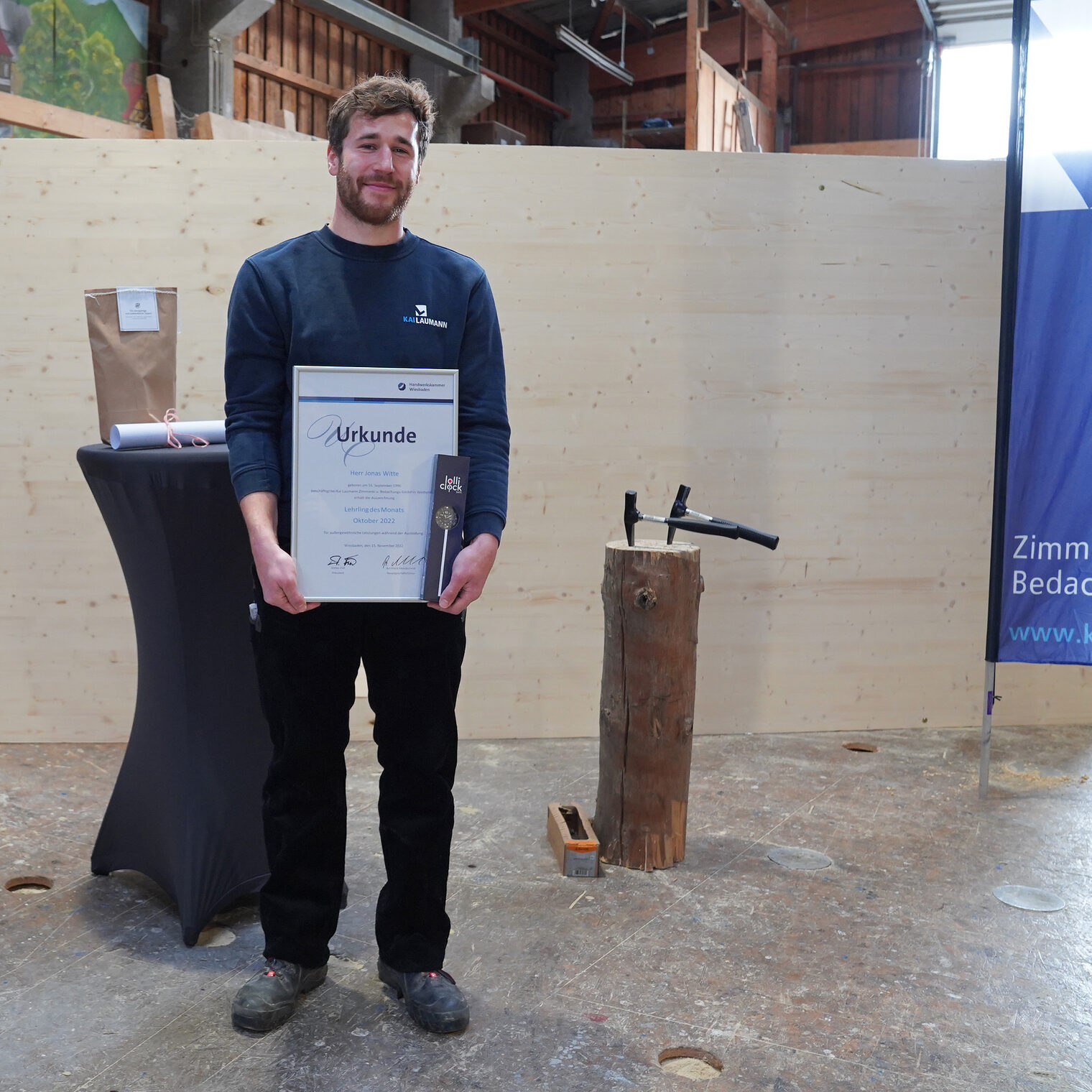 Jonas Witte ist von der Handwerkskammer Wiesbaden als Lehrling des Monats Oktober ausgezeichnet worden. Der 26-Jährige macht eine Ausbildung zum Zimmerer bei der Kai Laumann Zimmerei- und Bedachungs-GmbH begonnen. Auf dem Bild ist er in der Betriebshalle zu sehen mit seiner Urkunde.