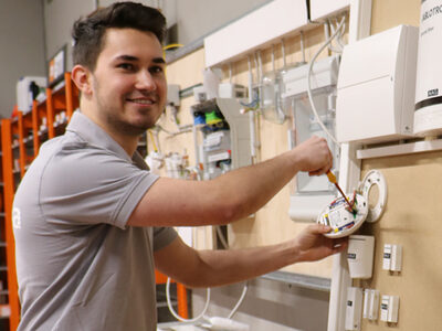 Profilbild eines jungen Mannes der an einer Elektroinstallationswand arbeitet.
