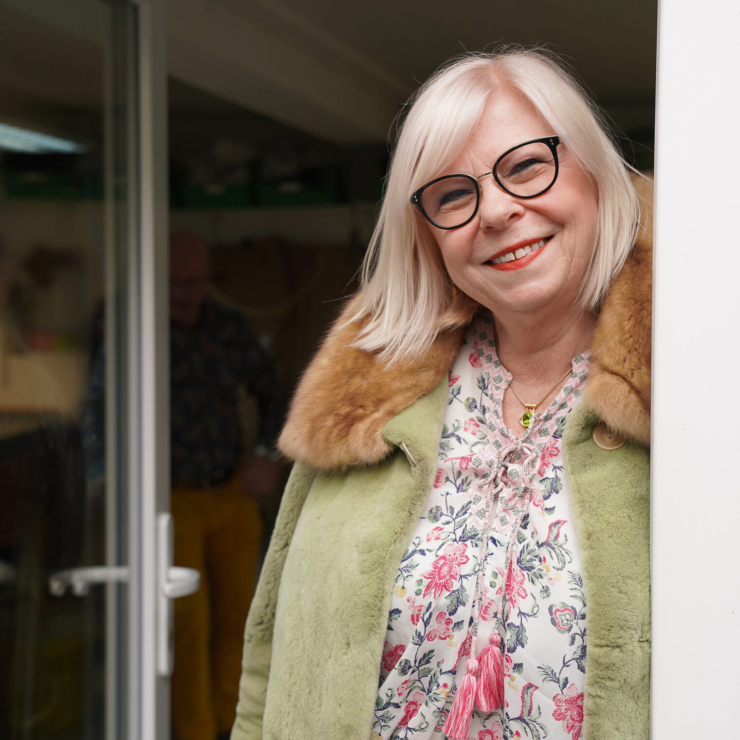 Im Bild steht Frau Gertrud Picha Kürschnermeisterin, in der Tür zu ihrem Atelier mit einem ihrer Pelzjacken und lächelt in die Kamera. 