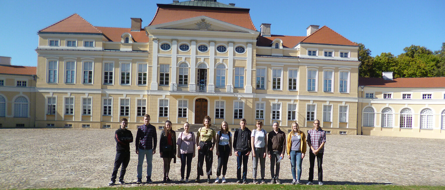 Gruppenfoto von Jugendlichen die nebeneinander stehen. in der Außenanlage vor einem großen historischen Gebäude in Posen.