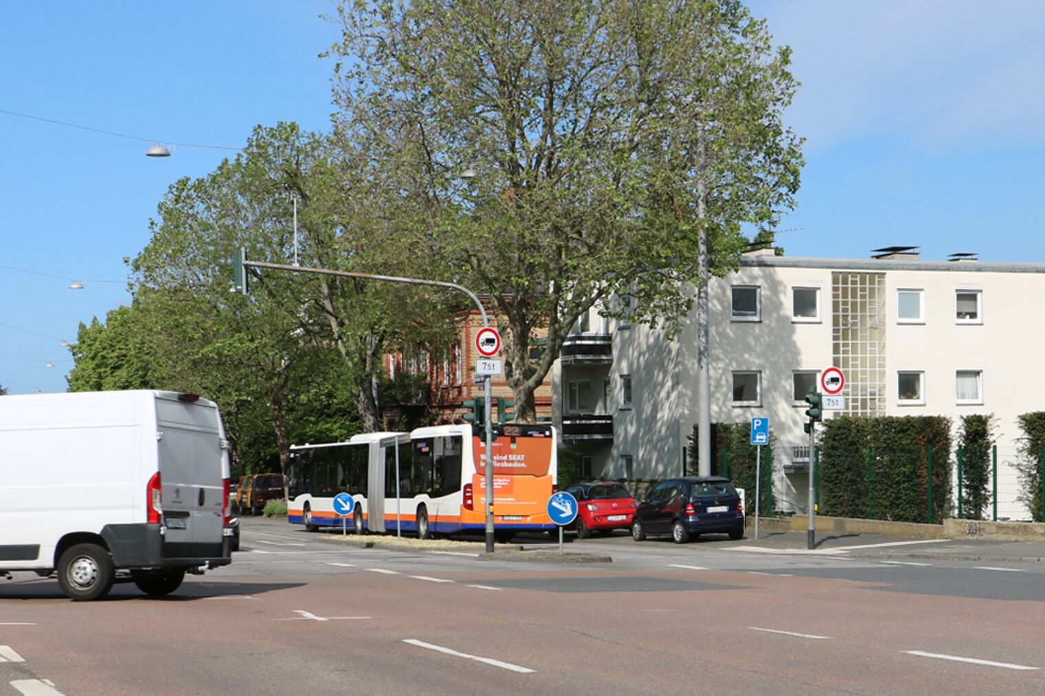 Zwei weiße Lieferbusse überqueren eine Straßenkreuzung.