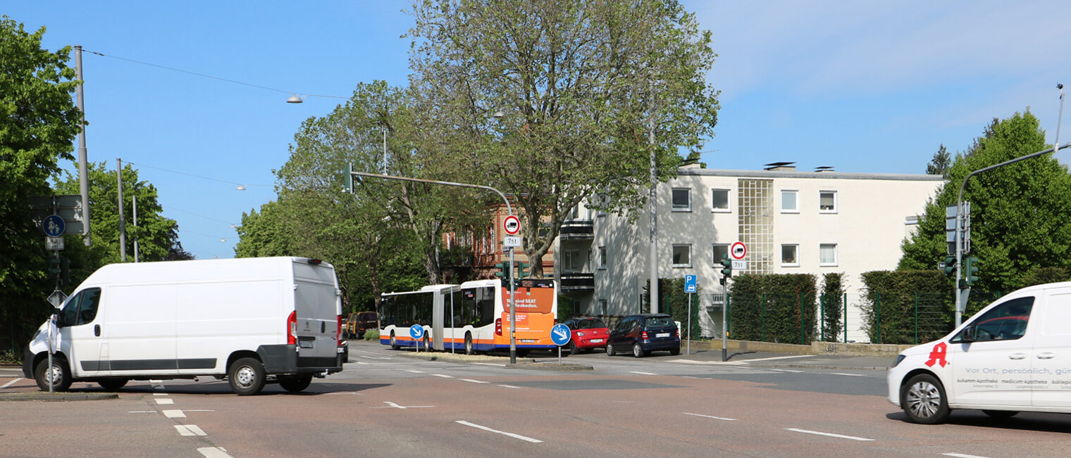 Zwei weiße Lieferbusse überqueren eine Straßenkreuzung.