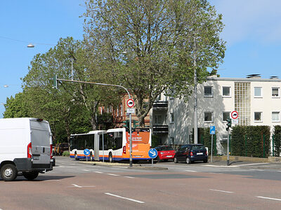 Zwei weiße Lieferbusse überqueren eine Straßenkreuzung.