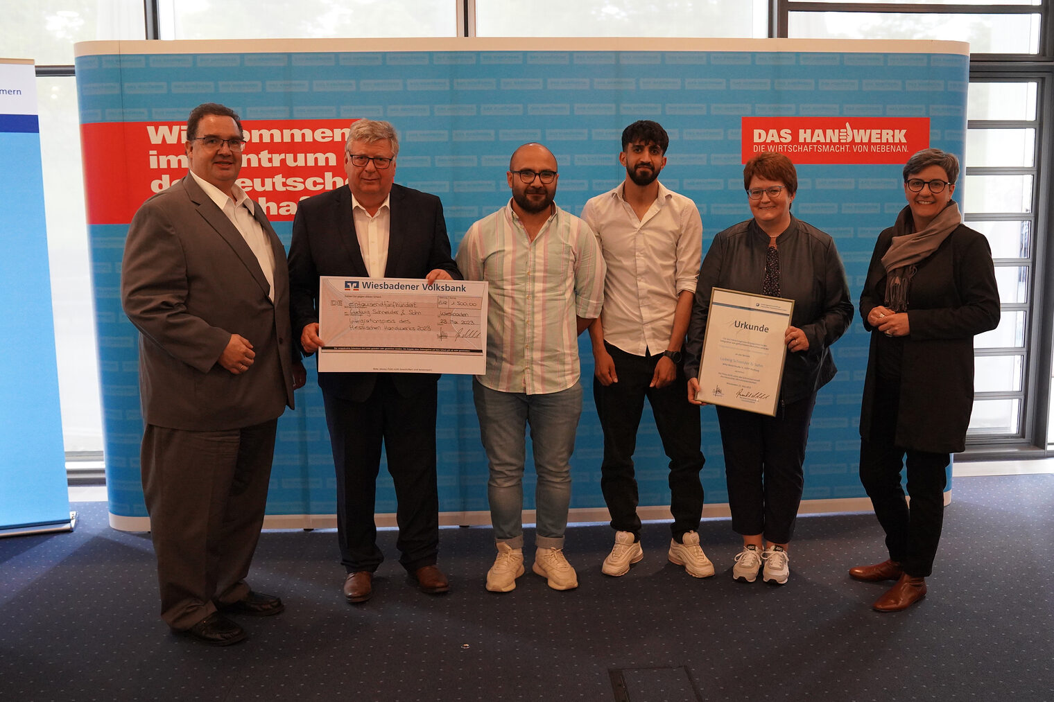 Gruppenfoto der Urkunden- und Scheckübergabe für den Hessischen Integrationspreis 2023 an die Firma Ludwig Schneider & Sohn aus Marburg.