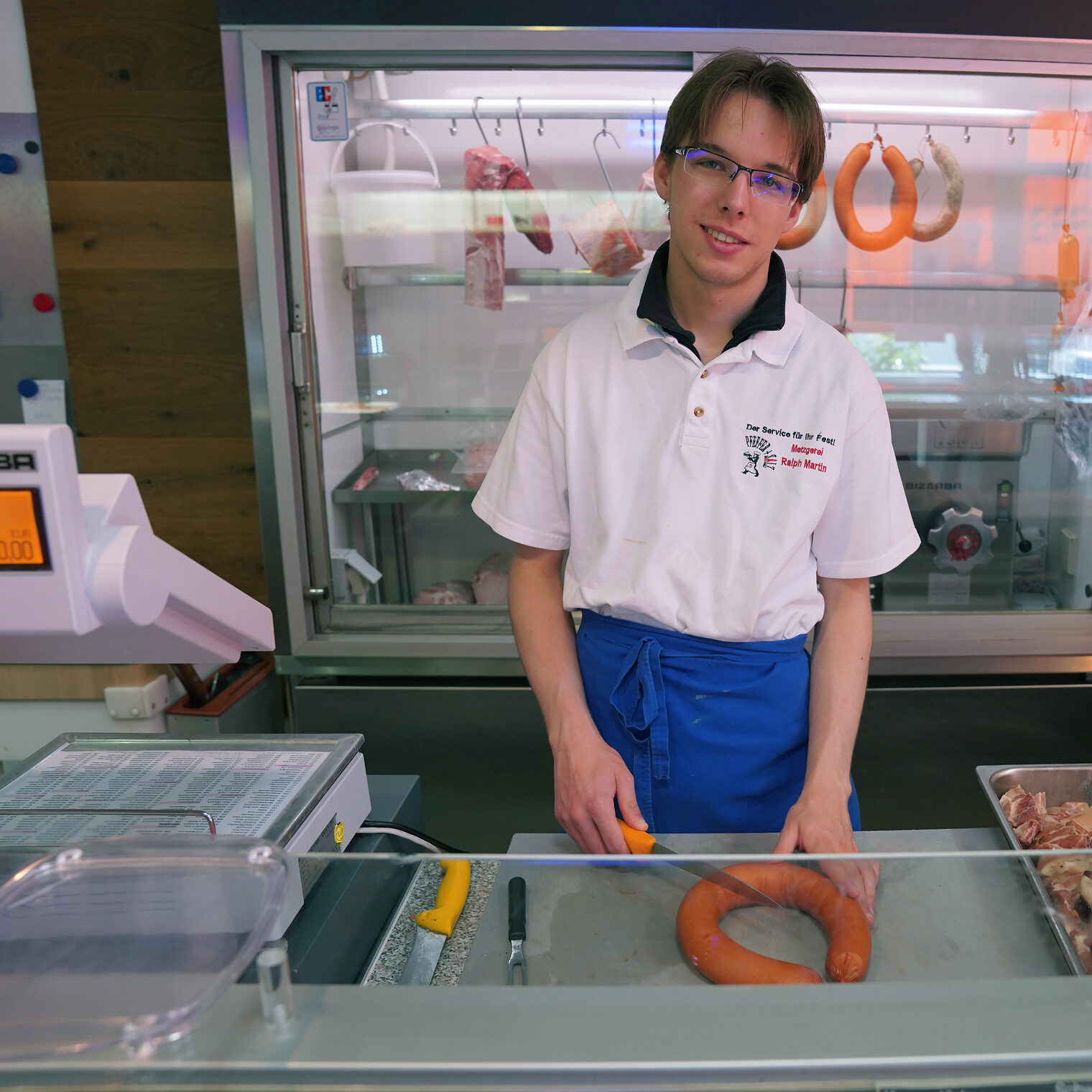 In der Metzgerei Ralph Martin in Frauenstein sammelte Damien Levillain Berufserfahrungen. Hier ein Bild von ihm hinter der Theke beim Aufschneiden einer Fleischwurst.