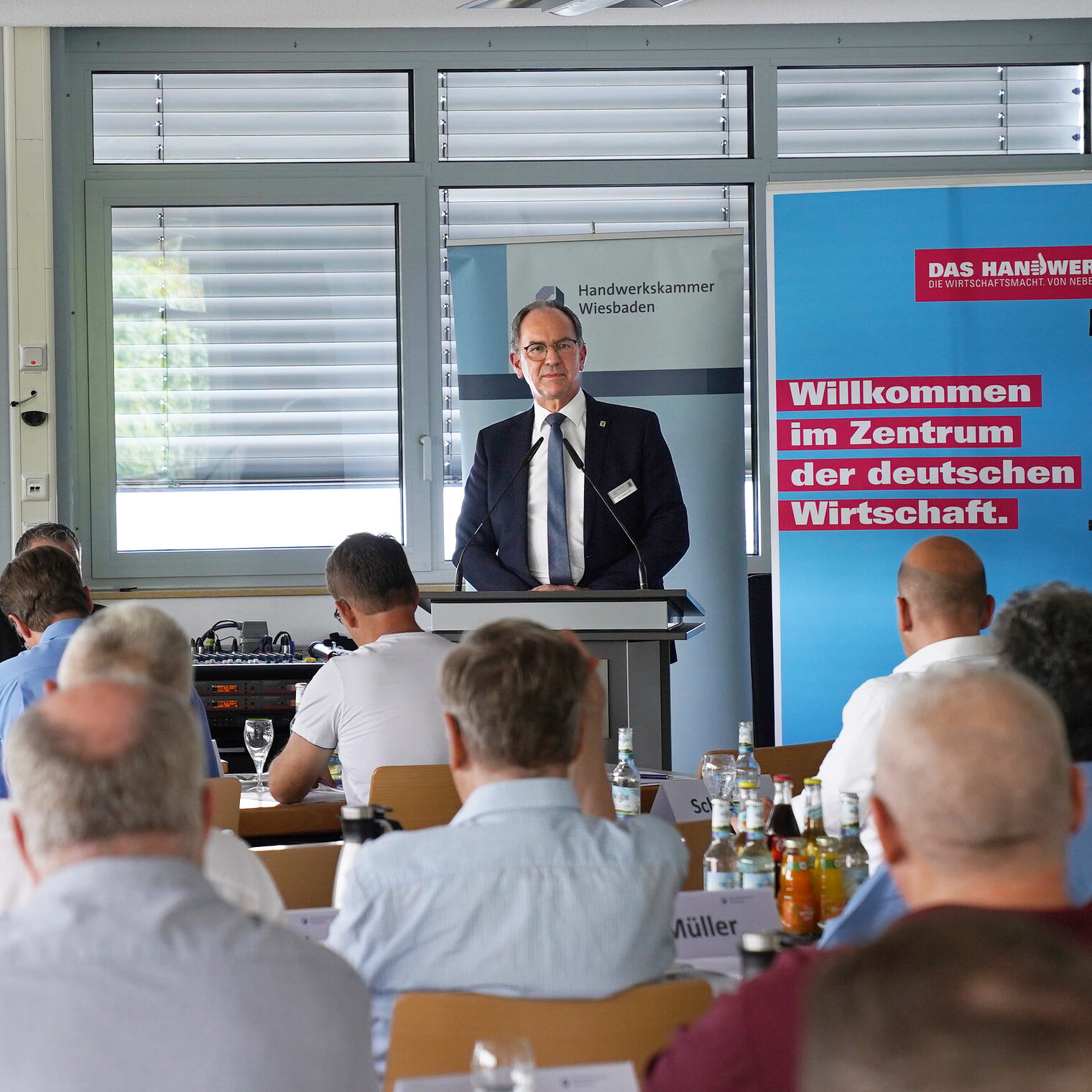 Regierungspräsident Dr. Christoph Ullrich hält auf der 150. Vollversammlung den Vortrag ¿Das Handwerk: Ein starkes Stück Mit-telhessen ¿ Chancen und Herausforderungen für die Wirtschaftsmacht von nebenan¿. Auf dem Bild ist er an einem Rednerpult zu sehen. 