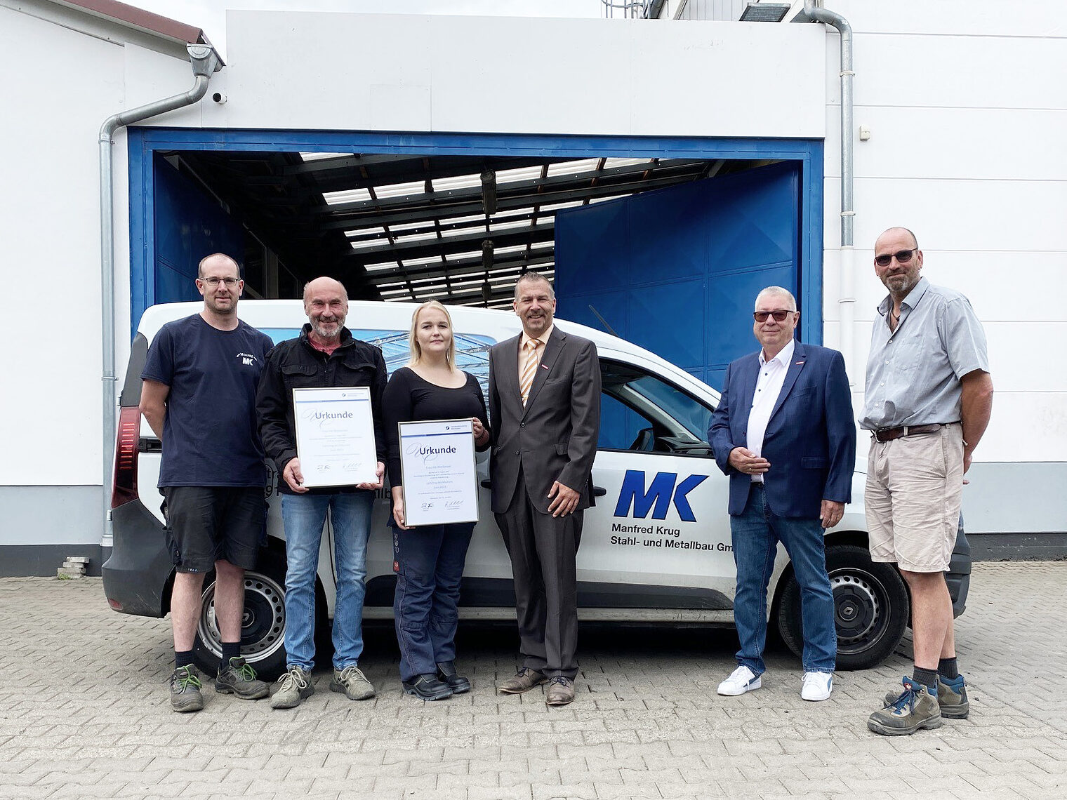 Gruppenbild nach der Auszeichnung von Ina Weckesser vor dem Firmengebäude und einem Firmenwagen: von links nach rechts Geschäftsführer und Ausbilder Barthel Philippi, Geschäftsführer Herbert Karl Krug, Lehrling des Monats Ina Weckesser, Vizepräsident der Handwerkskammer Wiesbaden Andreas Brieske, Kreishandwerksmeister der Kreishandwerkerschaft für den Vogelsbergkreis Edwin Giese und Geschäftsführer Torsten Frank