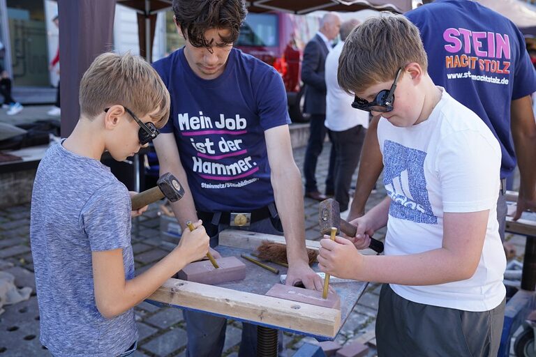 Aktionsbilder von der Veranstaltung "Handwerk live" 2023 in Wiesbaden. In den offenen Werkstätten konnten sich Jugendliche über das Handwerk informieren, sich ausprobieren und Kontakte knüpfen. Die Bilder zeigen verschiedene Jugendliche in und um das Berufsbildungs- und Technologiezentrum in Wiesbaden am Tag des Handwerks. 