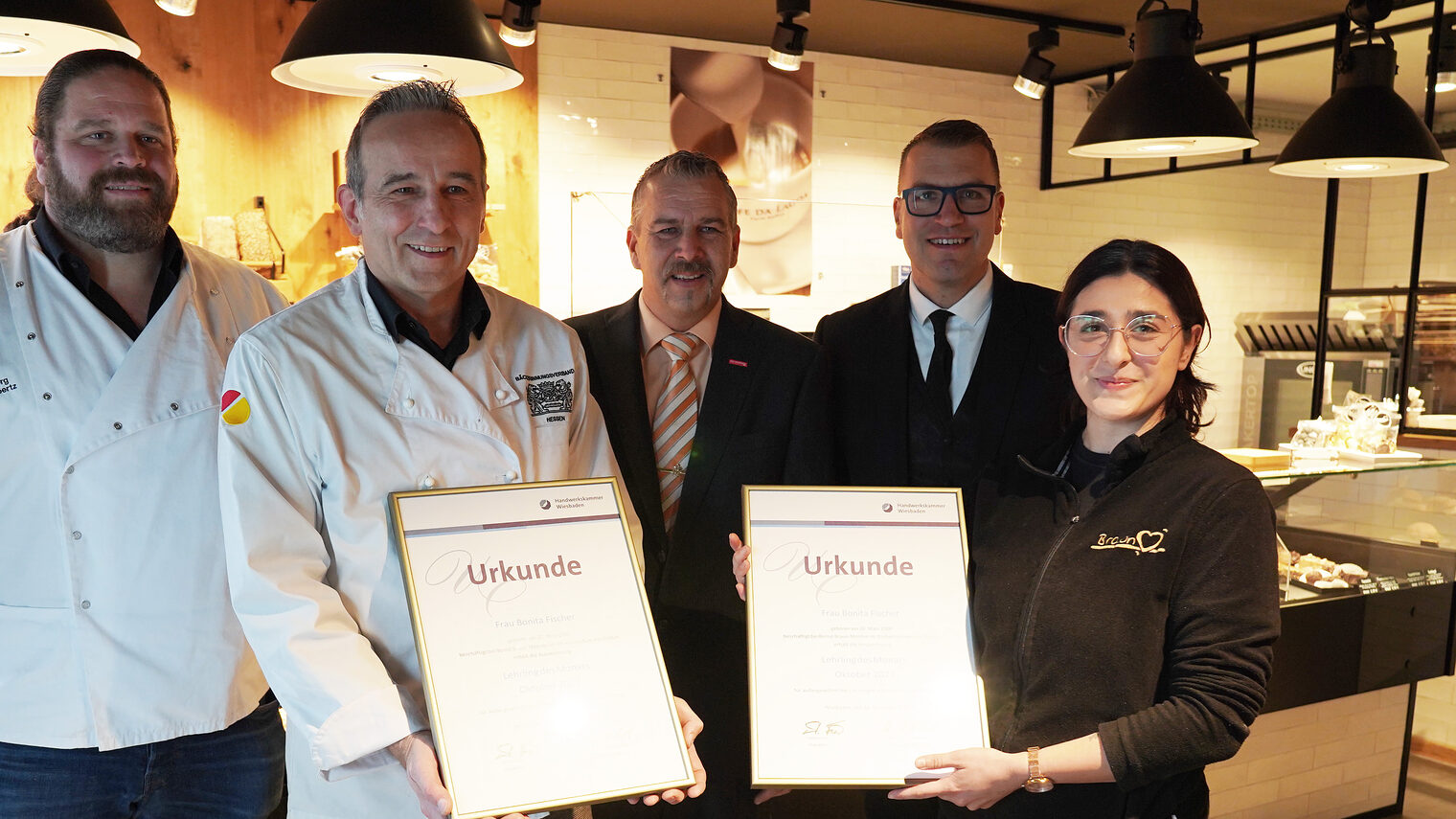 Gruppenfoto vor der Verkaufstheke des Cafés, v.l.n.re.: Sascha Prochazka, Bäckermeister Bernd Braun, Kammervizepräsident Andreas Brieske, stv. Obermeister Georg Lambertz und Lehrling des Monats Bonita Fischer mit Urkunden.