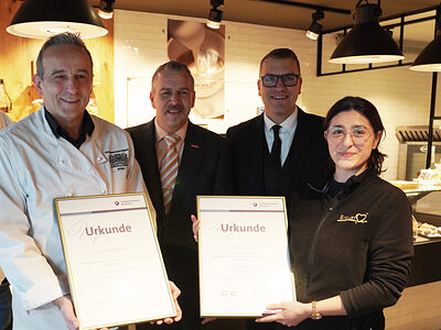 Gruppenfoto vor der Verkaufstheke des Cafés, v.l.n.re.: Sascha Prochazka, Bäckermeister Bernd Braun, Kammervizepräsident Andreas Brieske, stv. Obermeister Georg Lambertz und Lehrling des Monats Bonita Fischer mit Urkunden.