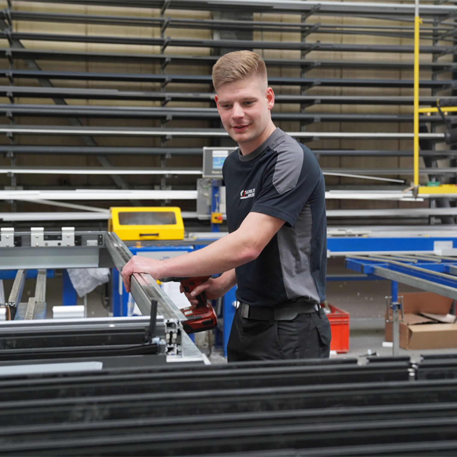 Noah Becker, frischgebackener Lehrling des Monats März 2024, steht in der Werkstatt und schraubt ein Metallteil an.