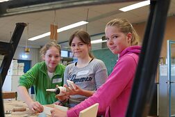 Drei Schülerinnen in der Holzwerkstatt unterstützen sich gegenseitig bei der Herstellung einer Holzkiste.