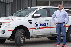 David Iflinger auf dem Firmengelände mit seinem Firmenwagen im Hintergrund.