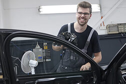 Lehrling des Monats Georg Wahl steht hinter einer geöffneten Autotür in der Kfz-Werkstatt.