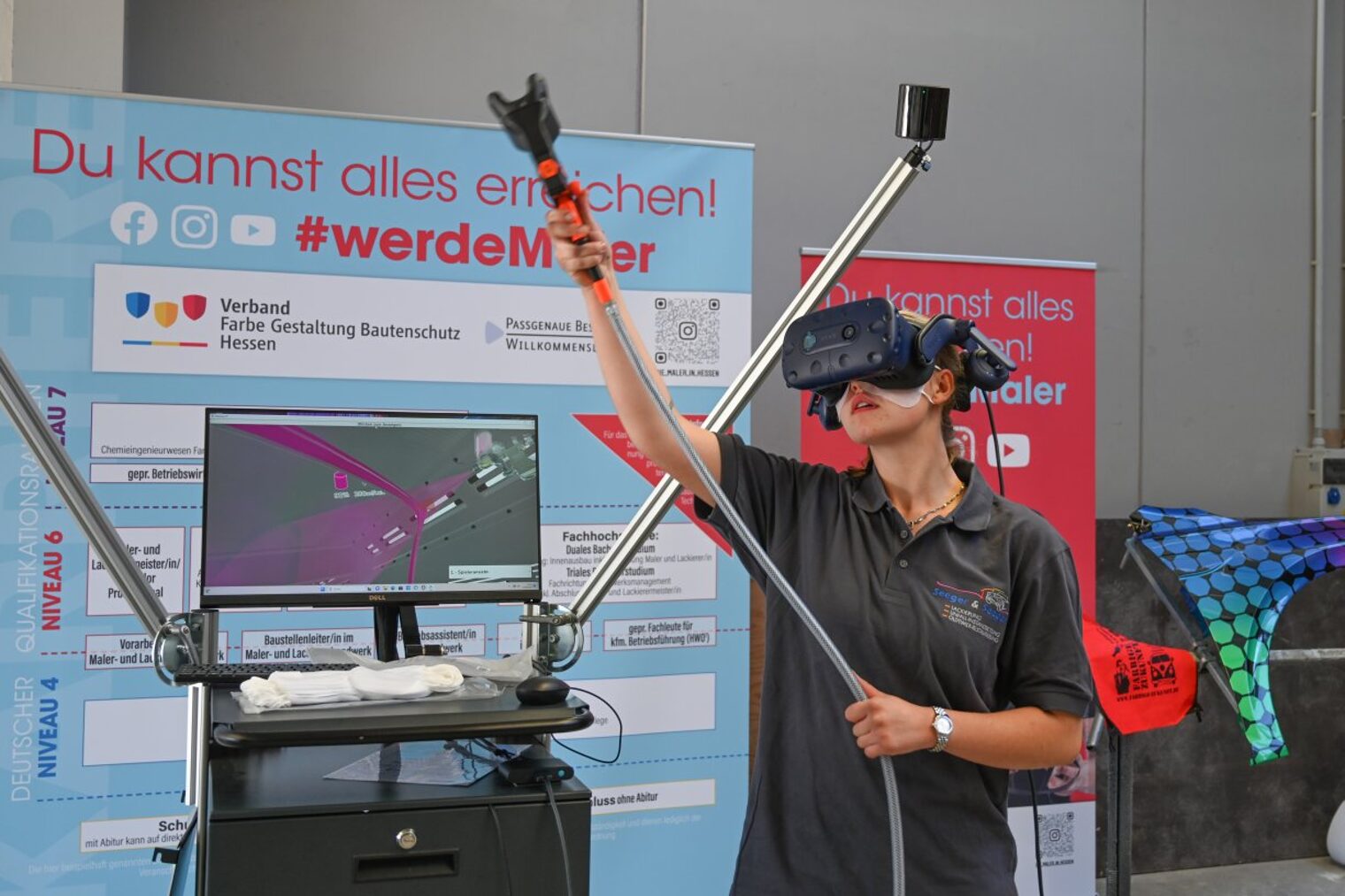Eine junge Frau verwendet eine VR-Brille um eine Tätigkeit im Malerhandwerk zu simulieren. 