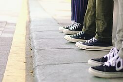 Füße in Turnschuhen auf einem Bürgersteig.