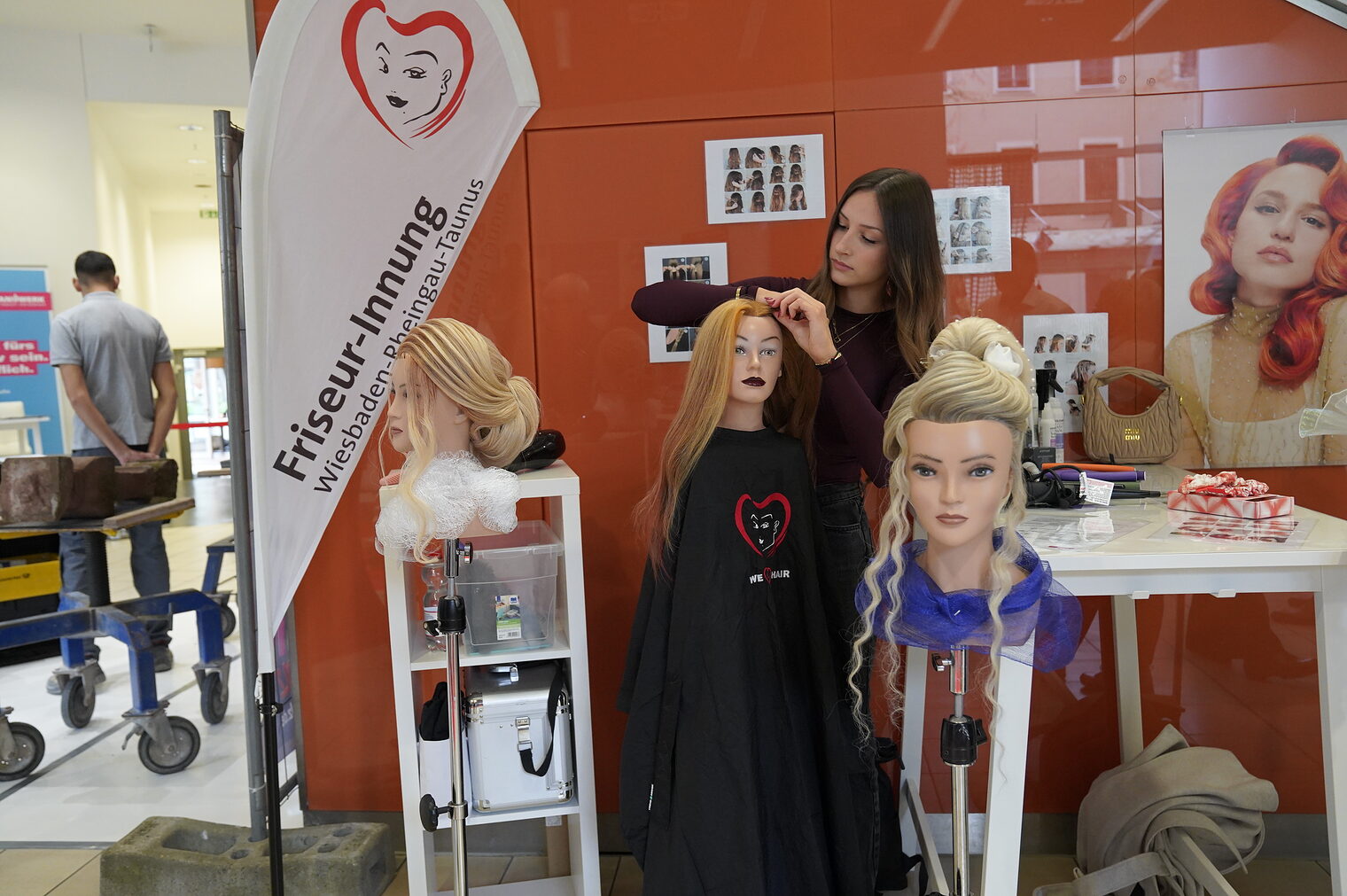 Eine Friseurin demonstriert an Frisurenköpfen ihr Handwerk.