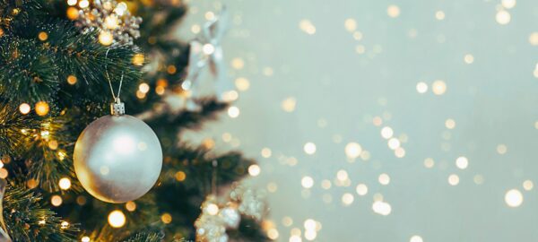 Weihnachtskugel am Weihnachtsbaum mit Lichtern und Glitzern im Hintergrund