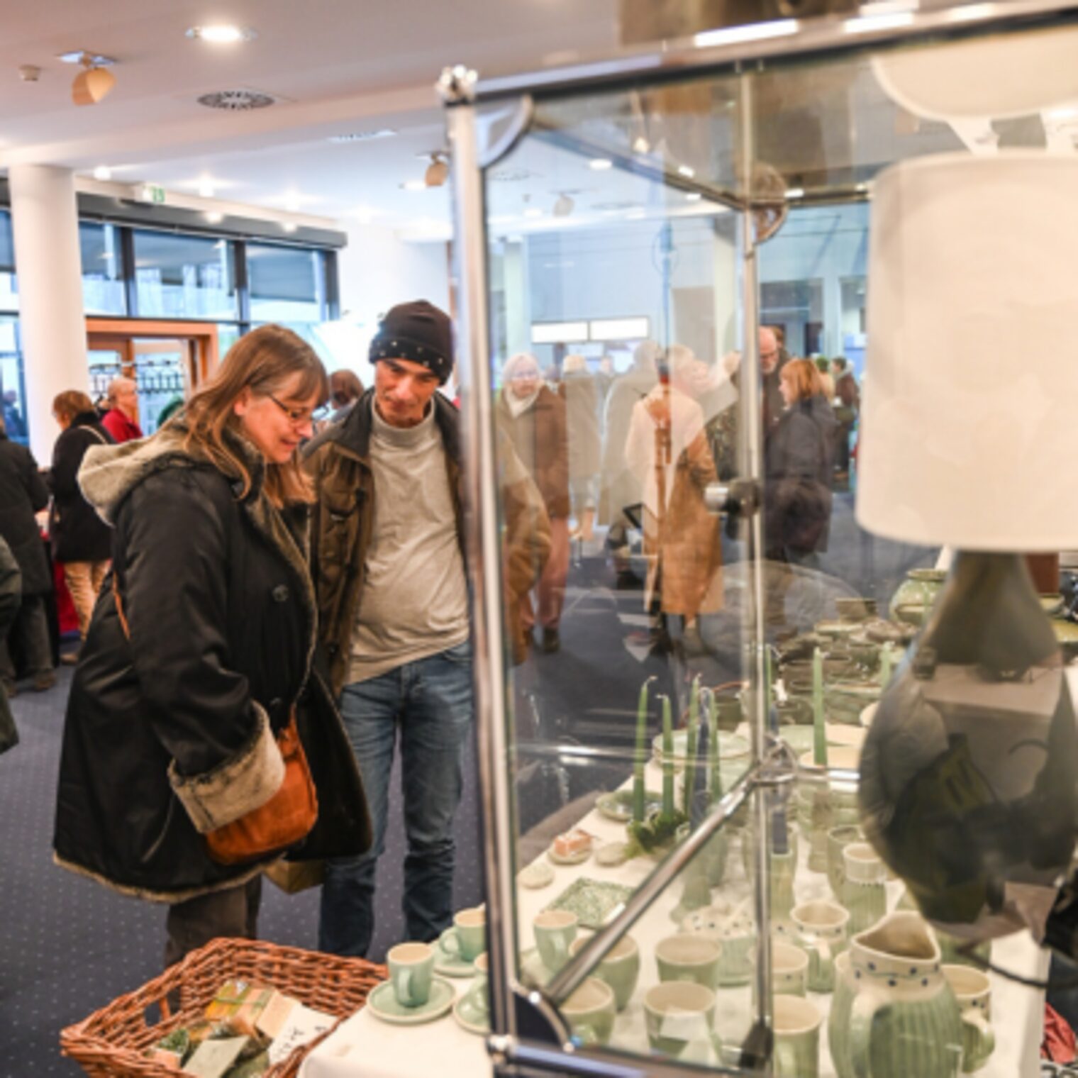 Vor dem Stand von dem Keramik Atelier Erbslöh aus Geisenheim vertreten durch die Meisterin im Keramikerhandwerk Gudrun Vogel, bewundern Teilnehmende Personen die einzelnen Stücke.