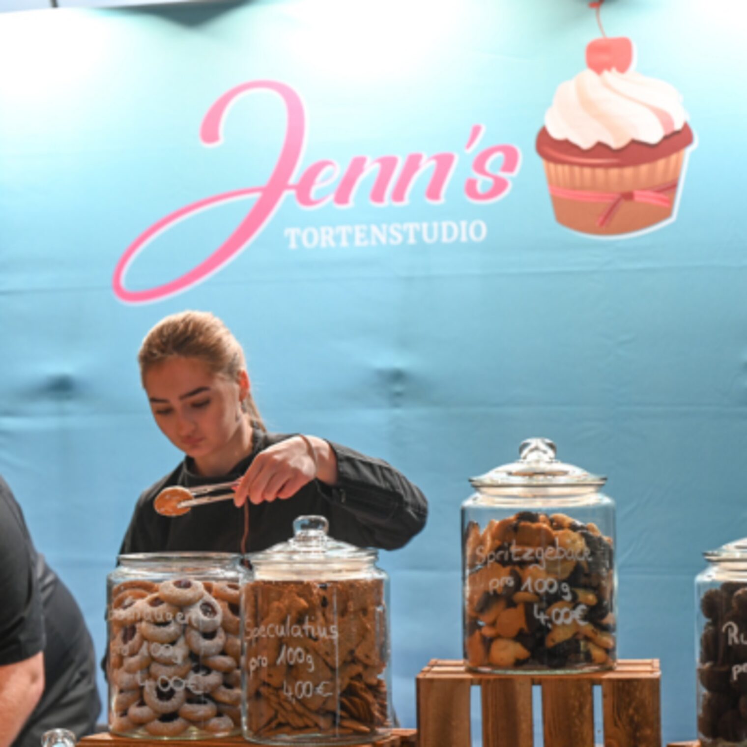 Jenn´s Tortenstudio aus Wiesbaden vertreten durch Jennifer Waidelich, Meisterin im Konditorenhandwerk vor Ihrem Stand mit einer Auswahl an Köstlichkeiten, darunter Spekulatius, Spritzgebäck und Rumkugekn.