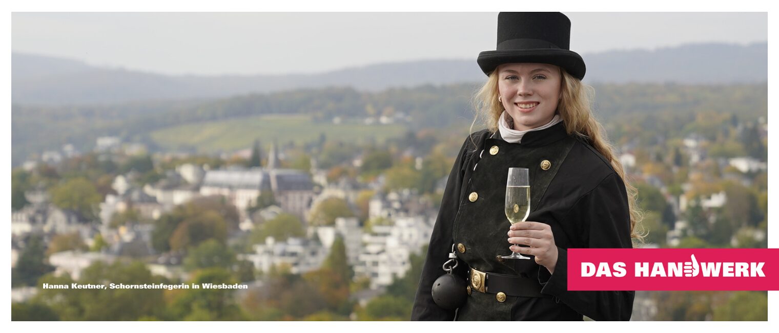 Das Bild zeigt Hanna Kreutner, Schornsteinfegerin, auf dem Dach mit einem Glas Sekt in der Hand.