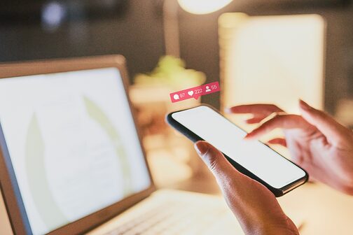 Eine Person sitzt von dem Laptop und gleichzeitig am Handy.