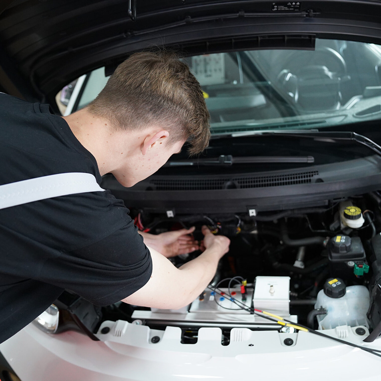 Ein Auszubildender arbeitet konzentriert an einem Auto.