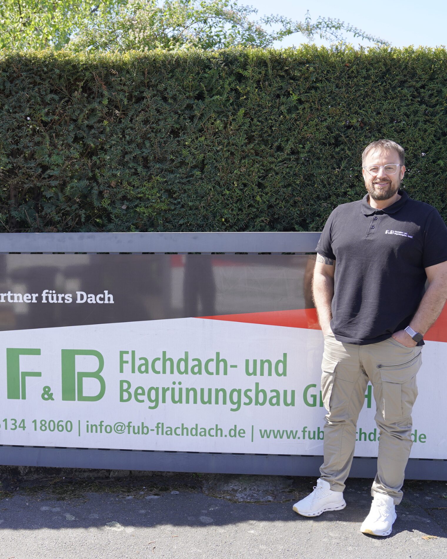 Sven Luft steht vor seiner Werkstatt an seinem Werbeschild. 