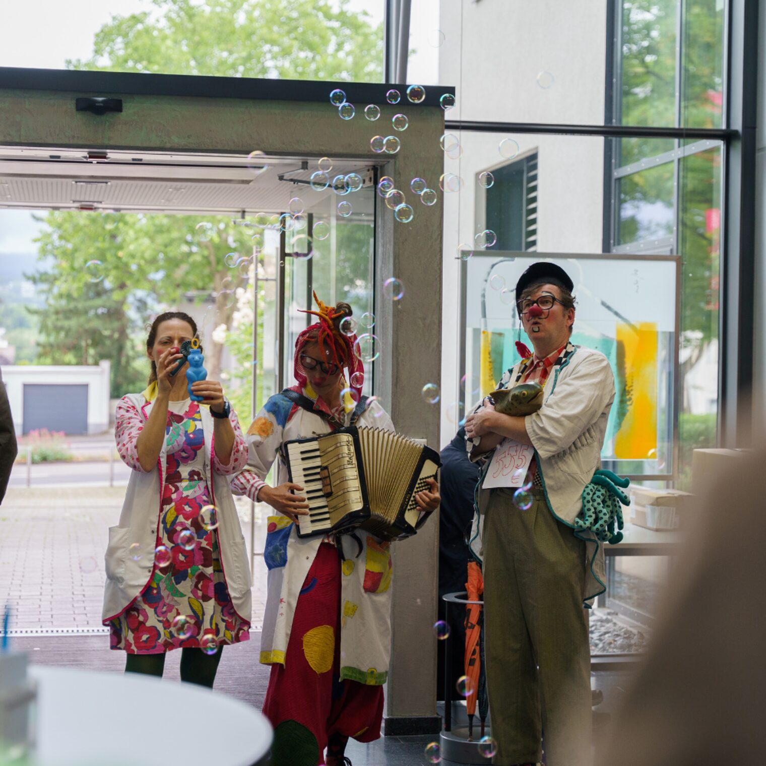 Drei Clowndoktoren die Seifenblasen in Publikum pusten.