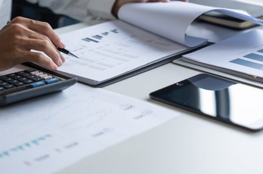 Ein Schreibtisch mit verschiedenen Vereinbarungen, Taschenrechner und einen IPad.