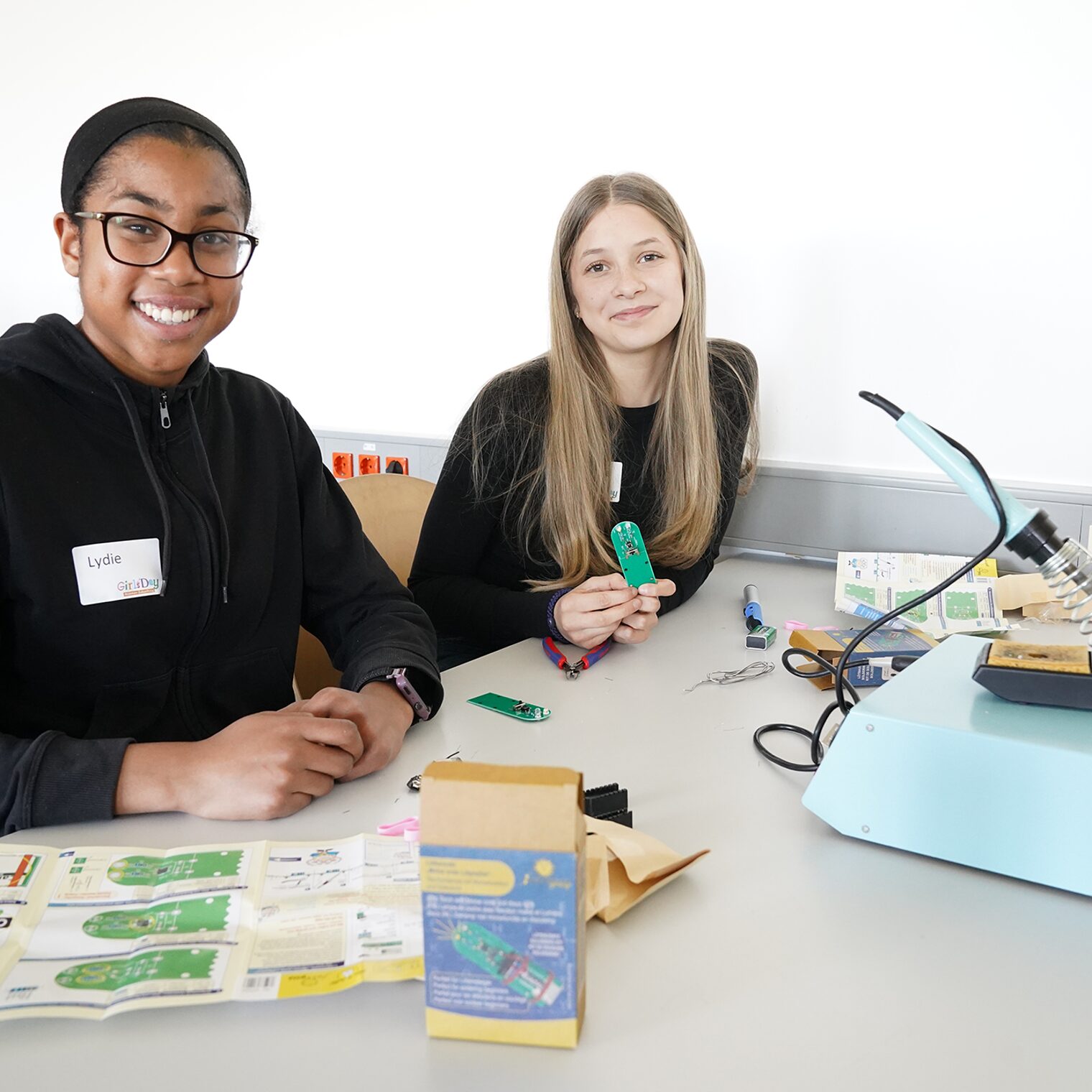 Zwei junge Frauen probieren sich in der Elektrowerkstatt aus und löten eine Platine