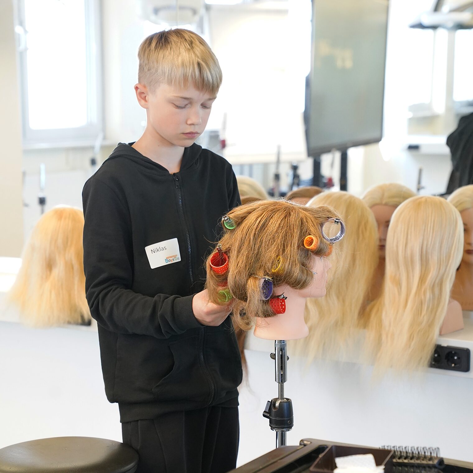Ein Schüler arbeitet konzentriert an einen Übungskopf im Schulungsraum der Friseure.