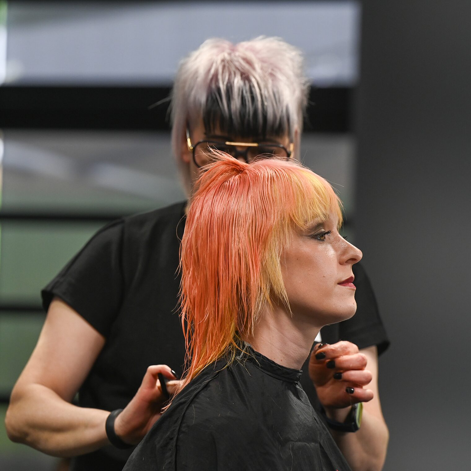 Friseurin schneidet an einem Model auf der Bühne die Haare.