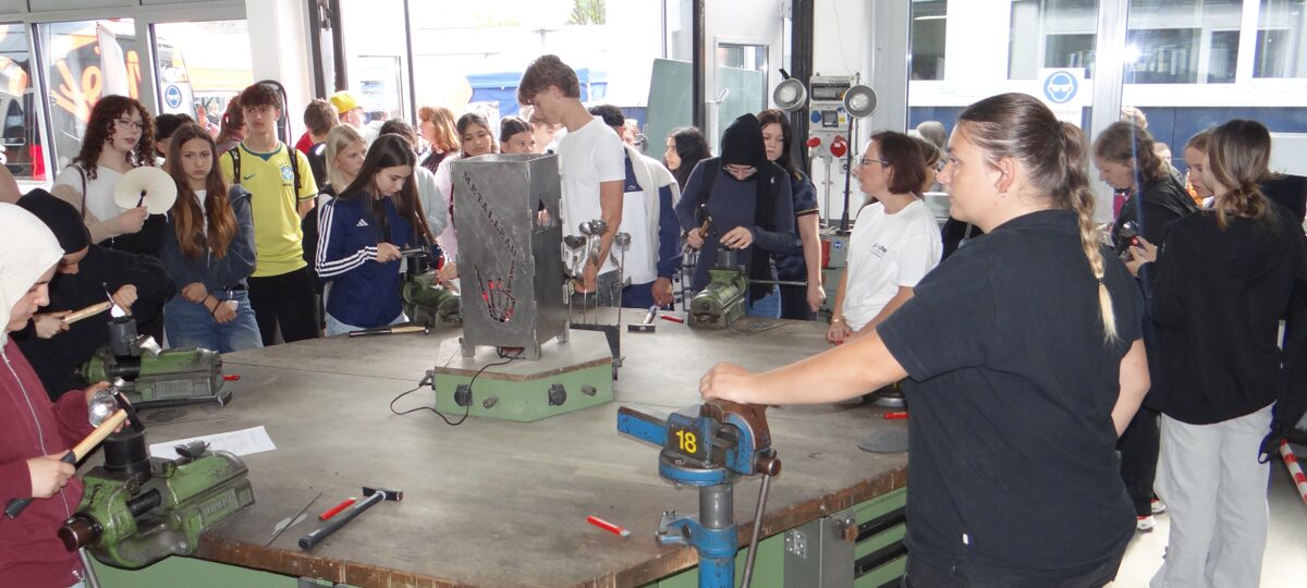 Schüler und Schülerinnen erkunden die Metallwerkstatt und probieren sich am Formen einer Metallrose.