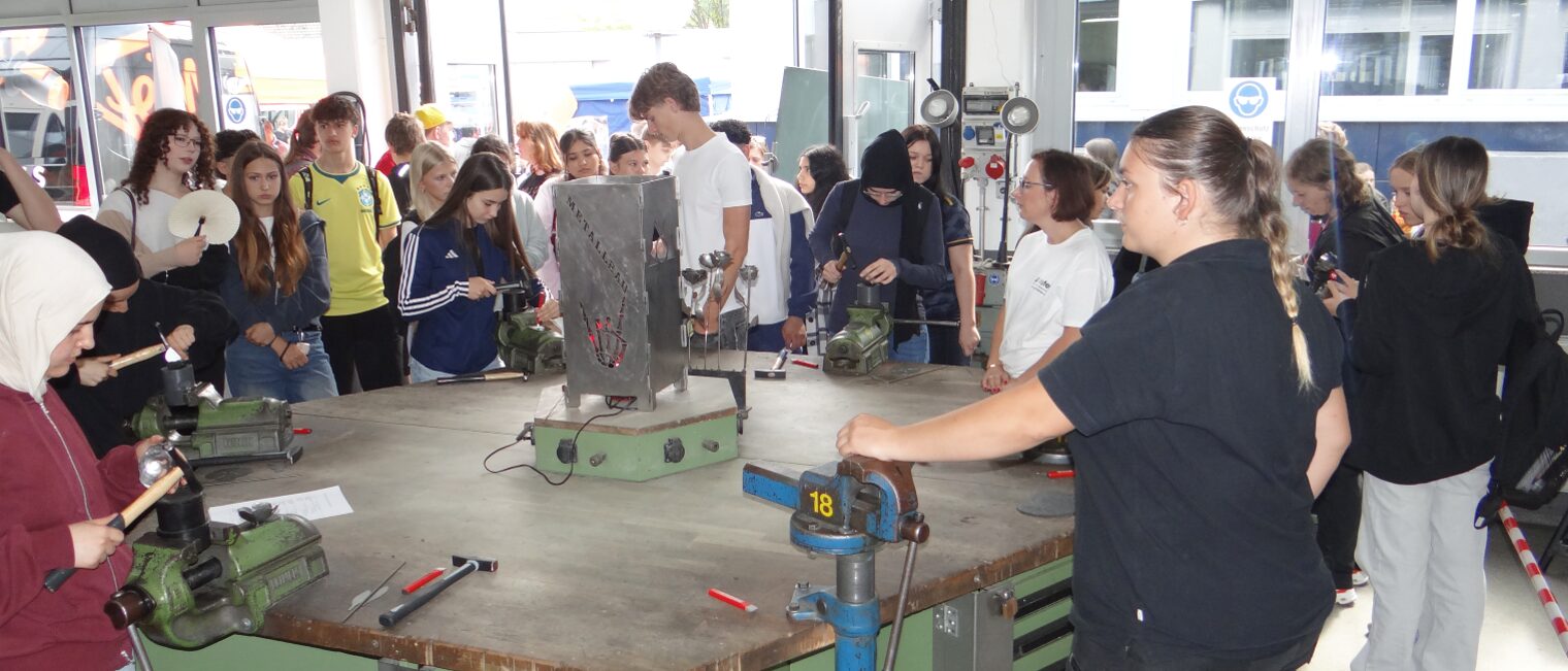 Schüler und Schülerinnen erkunden die Metallwerkstatt und probieren sich am Formen einer Metallrose.