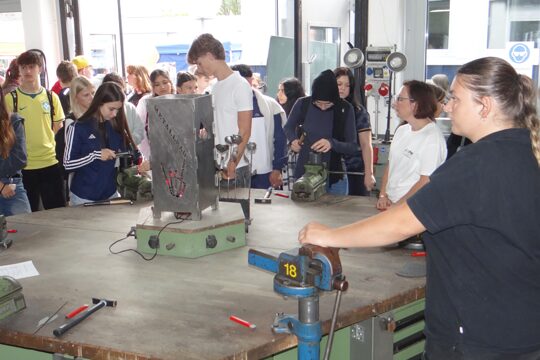 Schüler und Schülerinnen erkunden die Metallwerkstatt und probieren sich am Formen einer Metallrose.